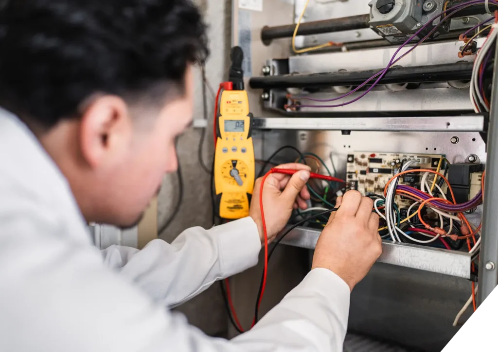 Reliable Home Comfort HVAC technician testing furnace wiring – AC Maintenance & Repair in Los Angeles.