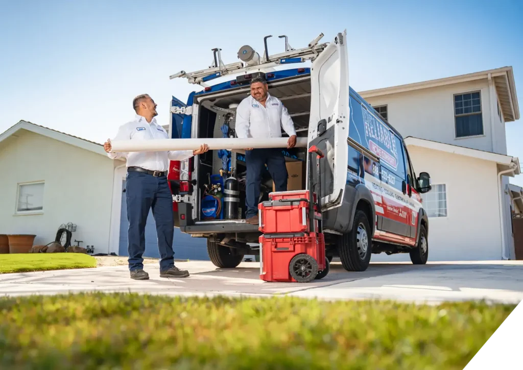 Reliable Home Comfort technicians unloading tools and materials from a fully equipped service van at a residential property in Downey, CA, ready to perform plumbing work.