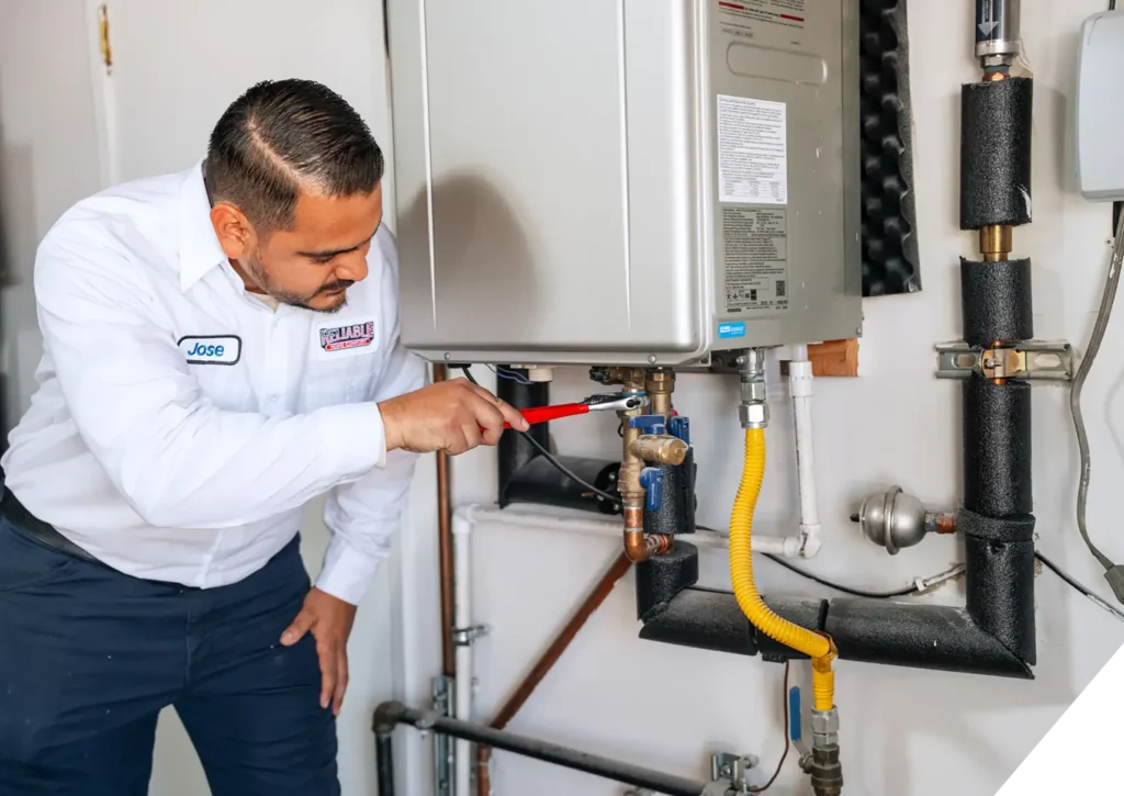 Reliable Home Comfort technician performing maintenance on a tankless water heater system in Garden Grove, CA.