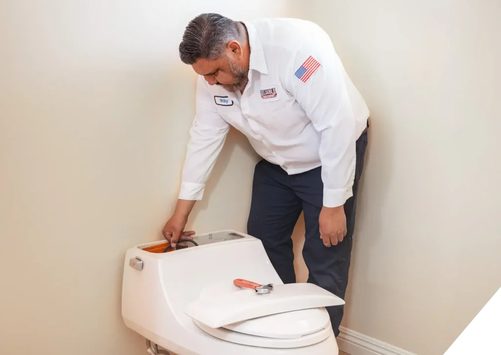 Reliable Home Comfort plumber inspecting a toilet tank for repair or replacement during a residential plumbing service in Yorba Linda, CA.